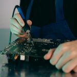 Person using a soldering iron on a printed circuit board.