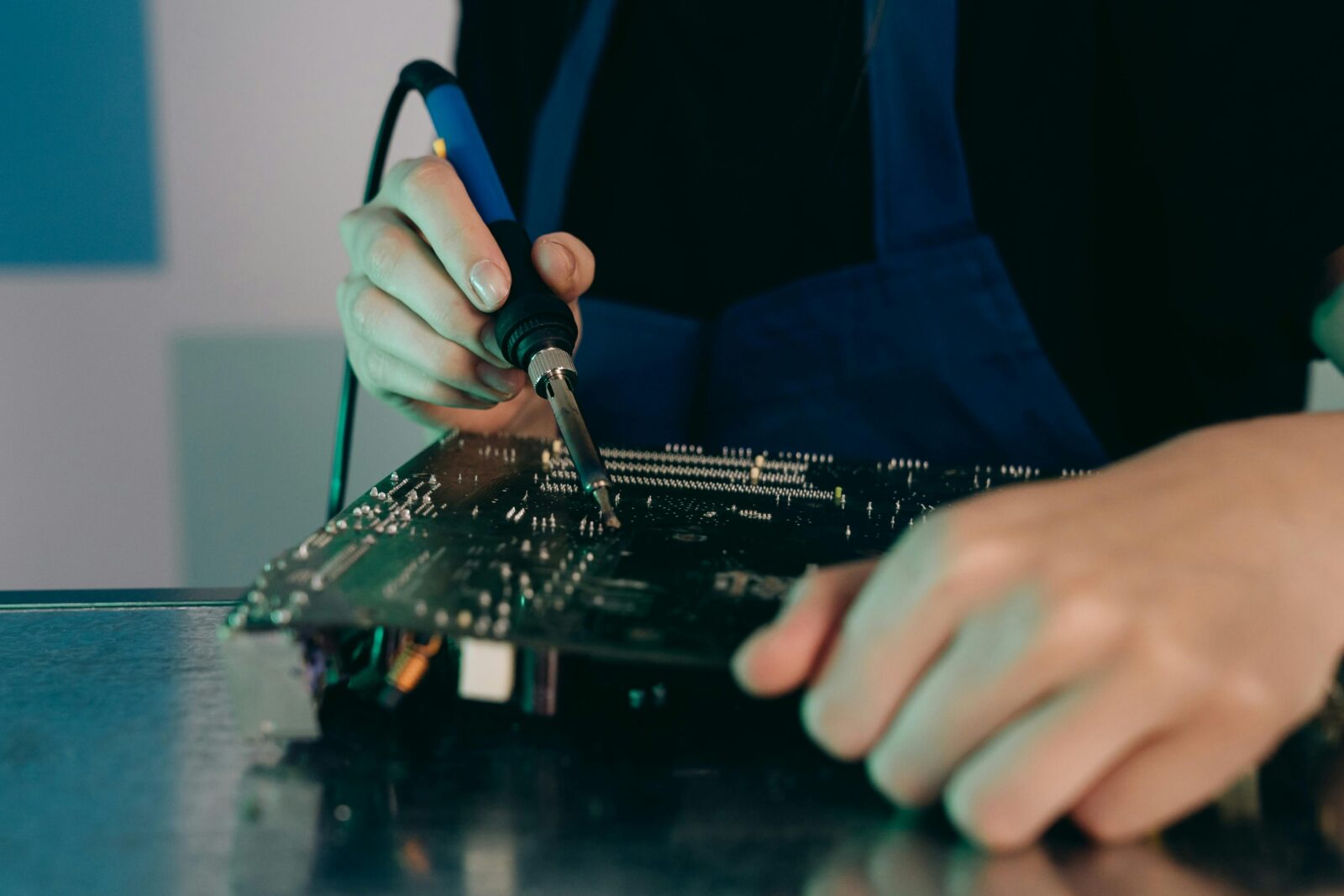 Person using a soldering iron on a printed circuit board.