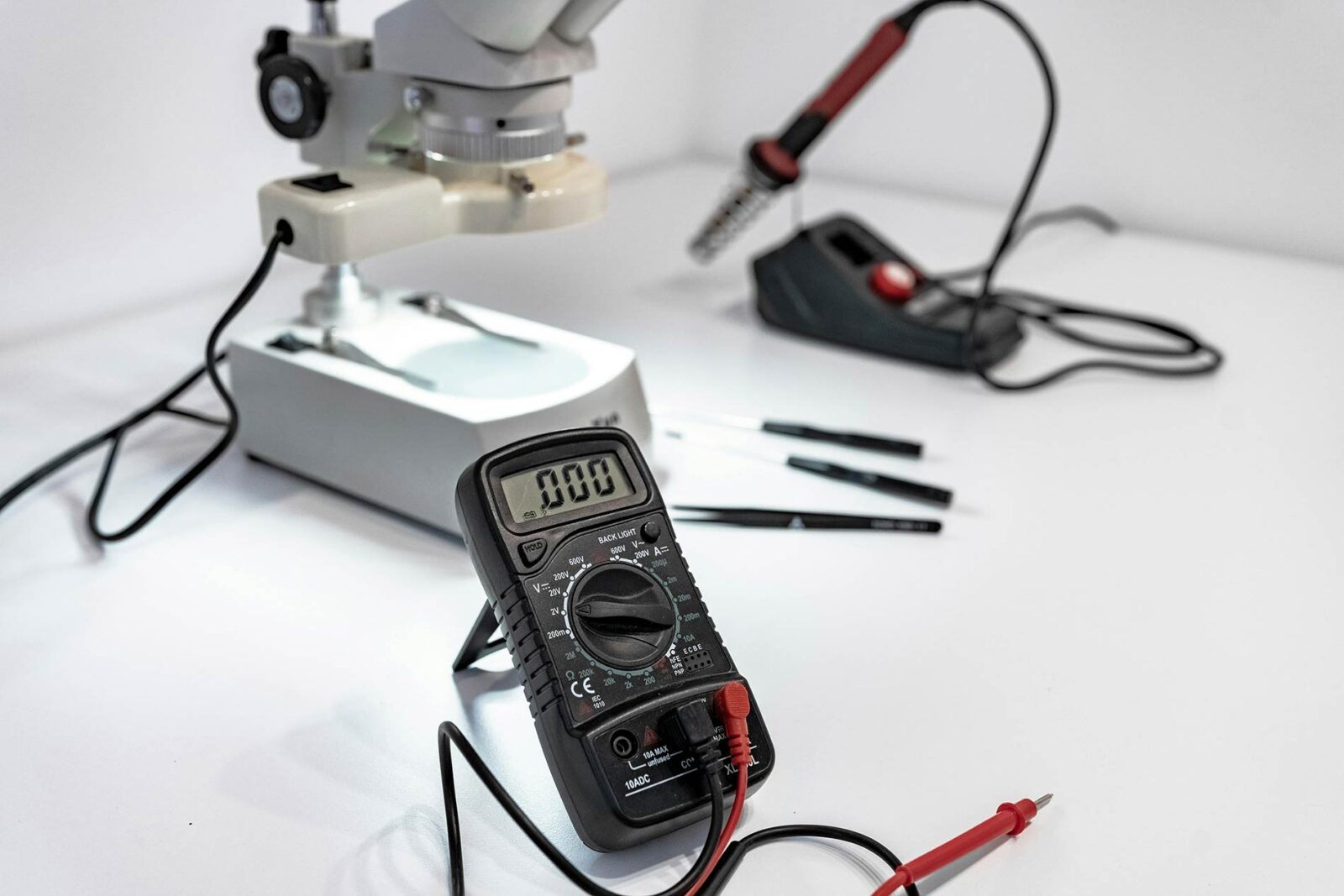 Multimeter, soldering iron, and microscope for electronics troubleshooting