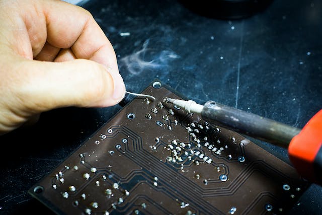 A person using a soldering iron on a device board