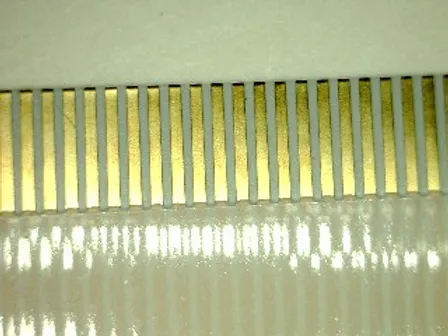 Close-up view of a flexible flat cable with gold-plated connector pins.