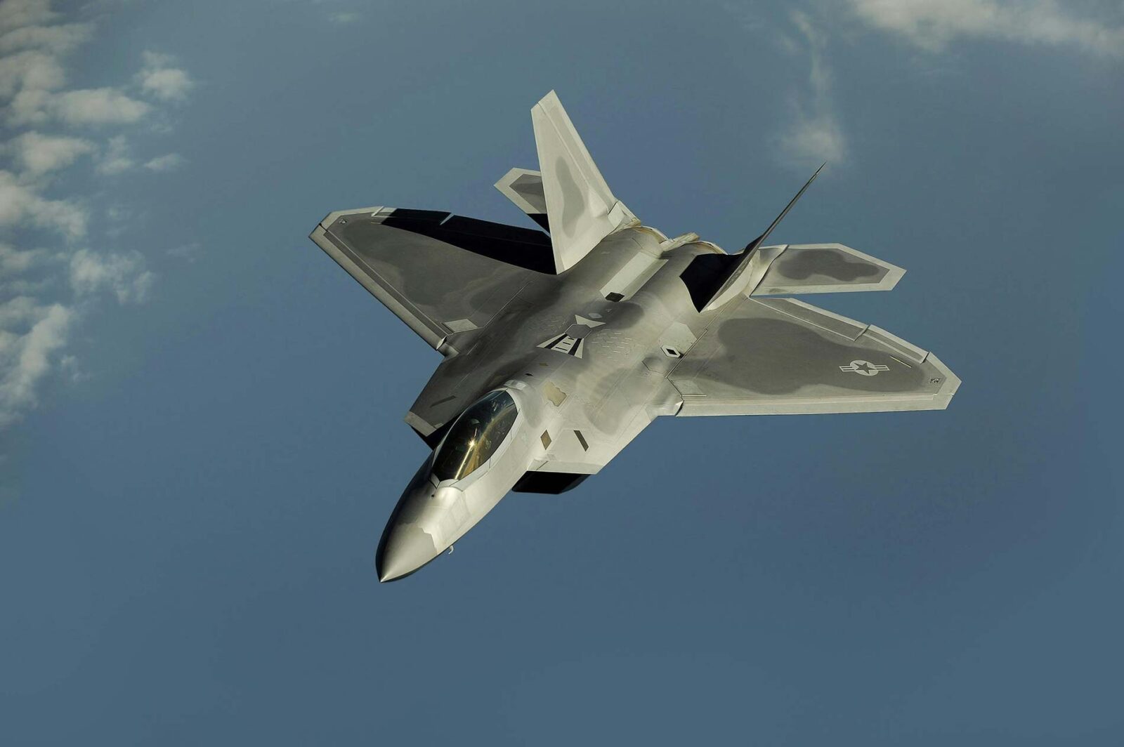 Gray USA fighter jet flying through blue sky.