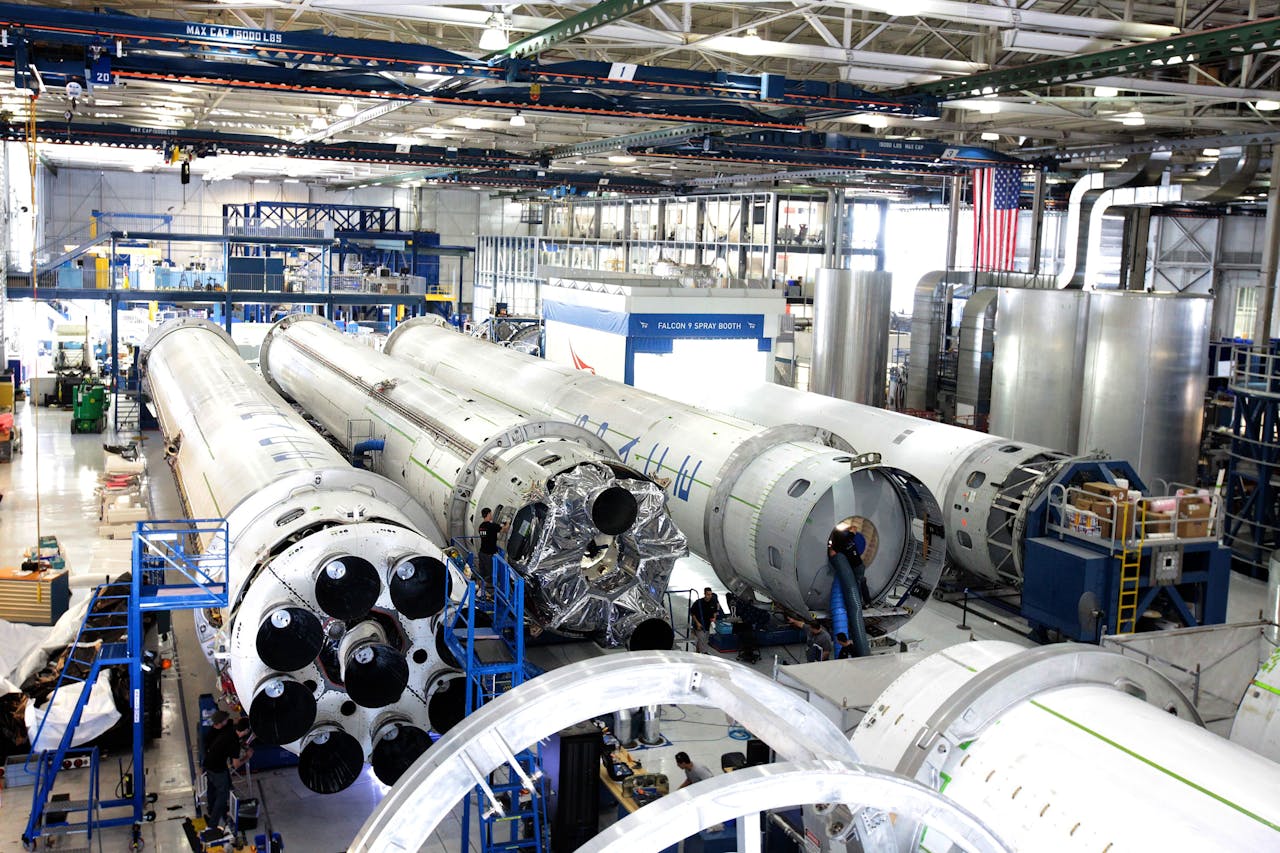Aerospace manufacturing facility with multiple rocket stages on the factory floor during assembly and processing.