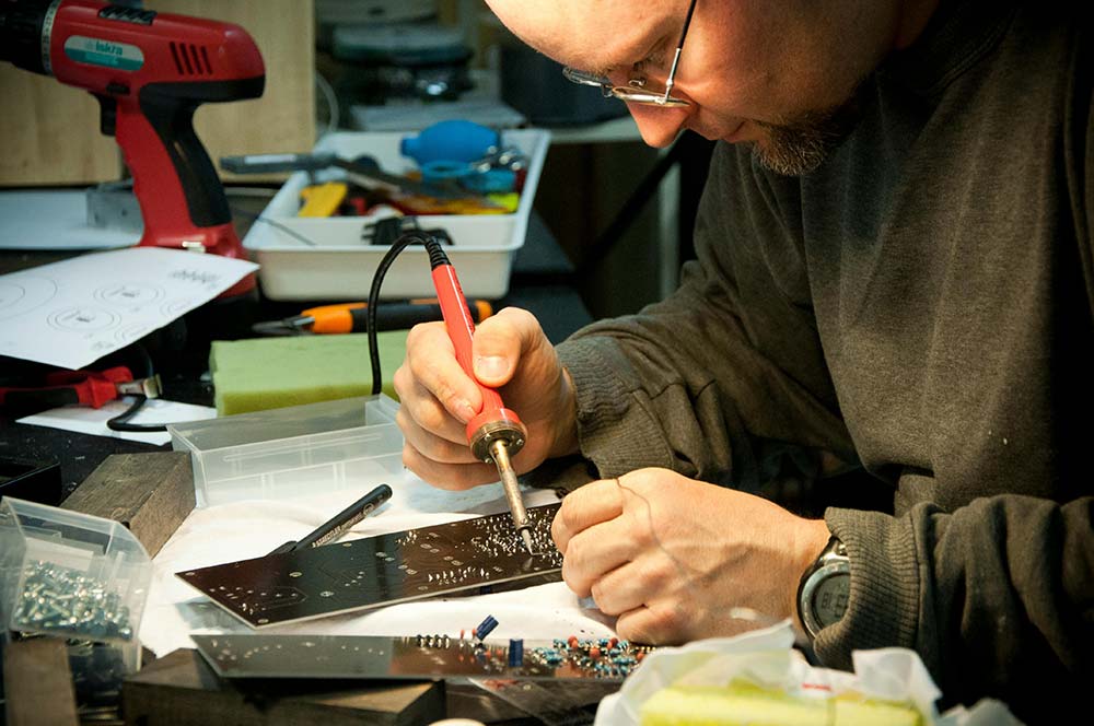 A man soldering a circuit board.